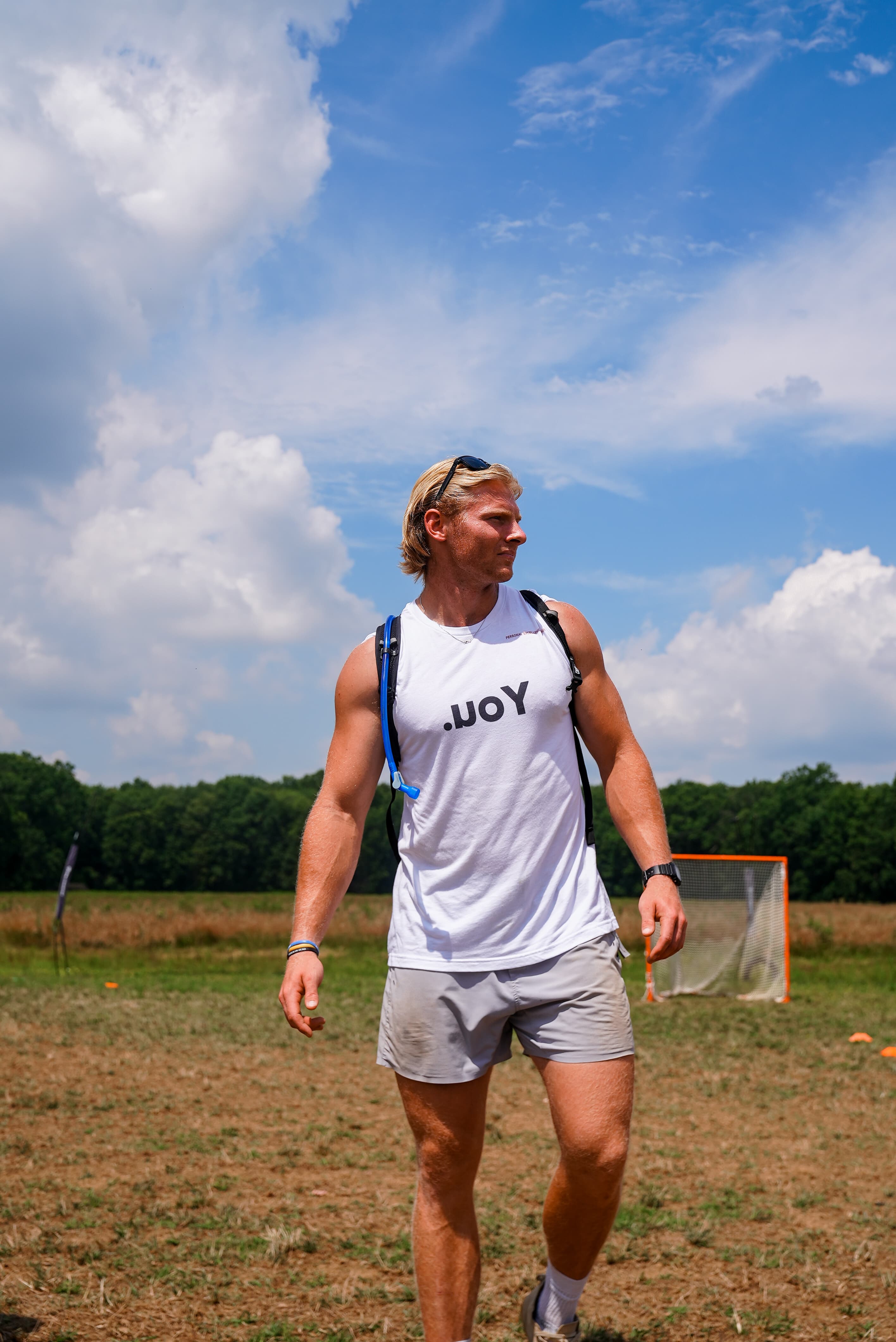 Harrison Schertzinger on the lacrosse field wearing a .uoY shirt under a blue sky
